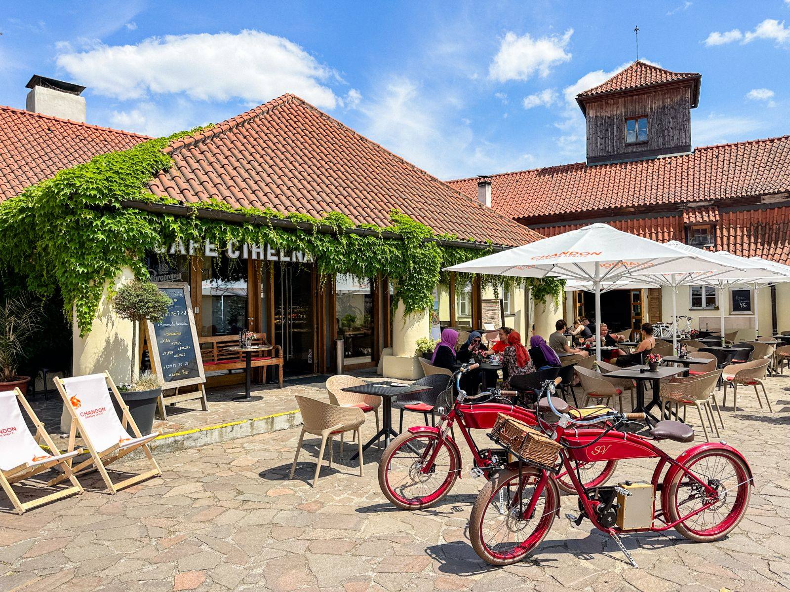 Café Cihelna’s ivy-covered entrance and terrace under a tiled roof