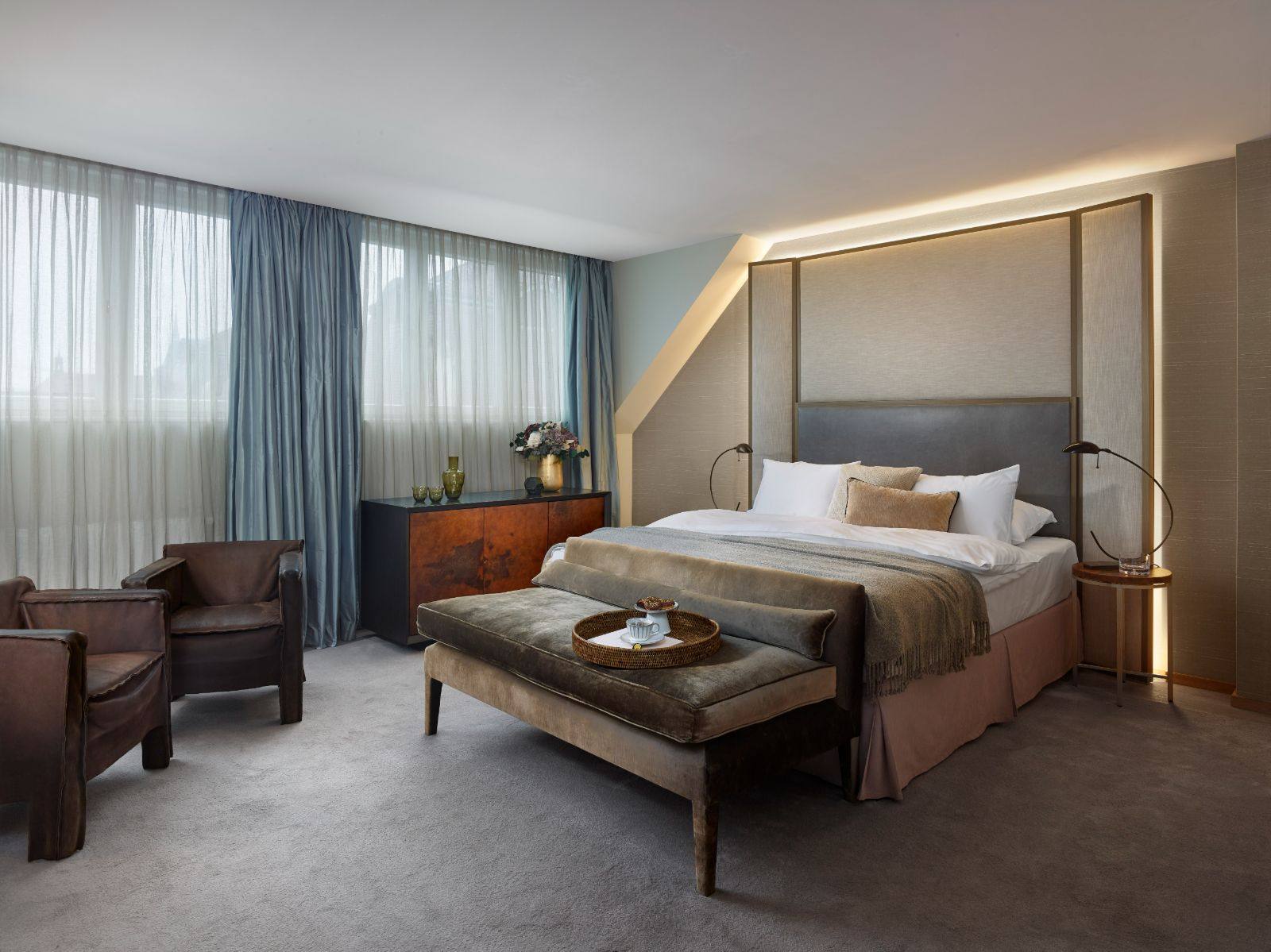 The Atelier room at The Emblem Prague hotel, with an illuminated headboard and velvet bench