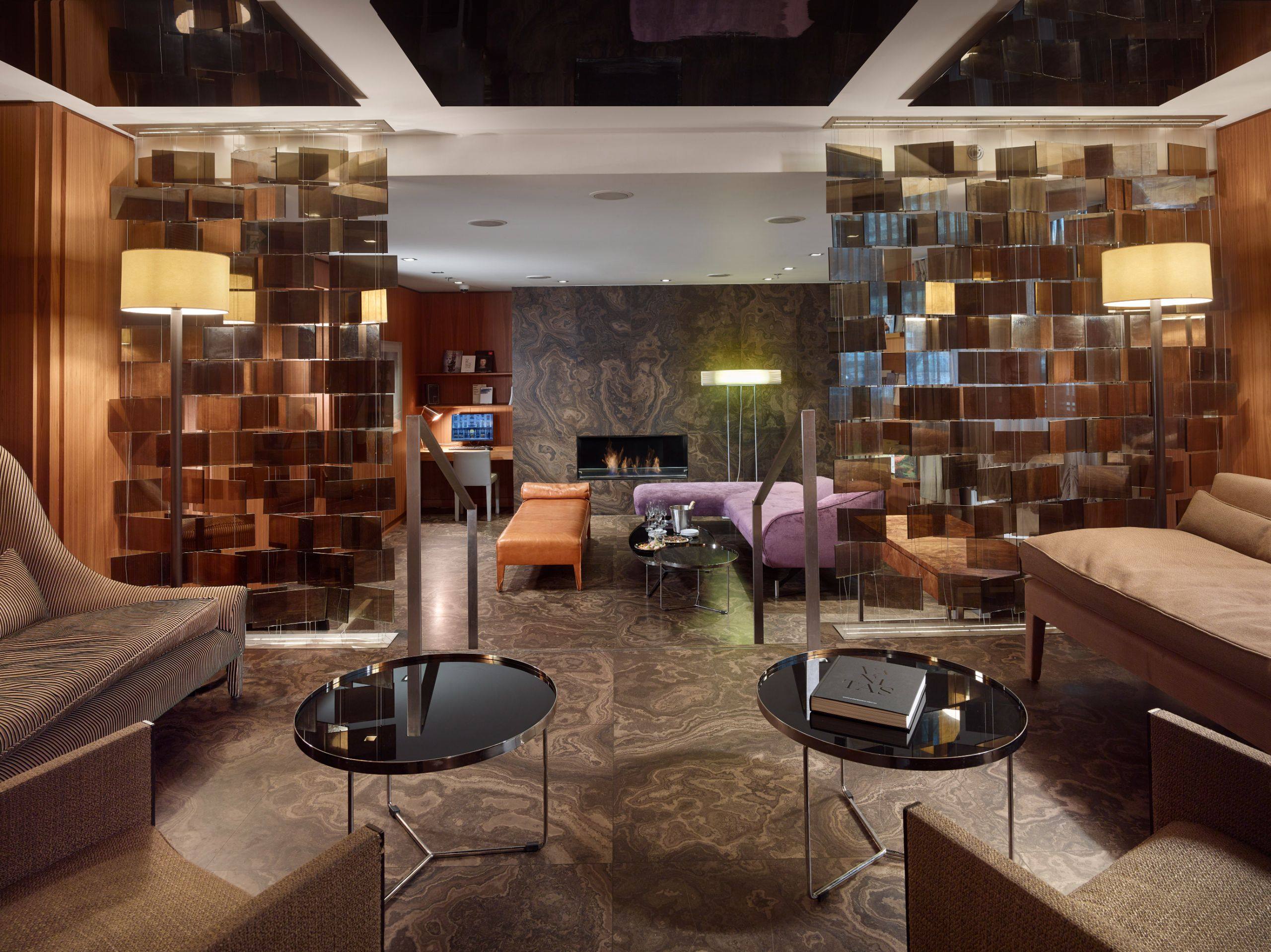 The lobby lounge at The Emblem Prague hotel, with fireplace and suspended glass screens