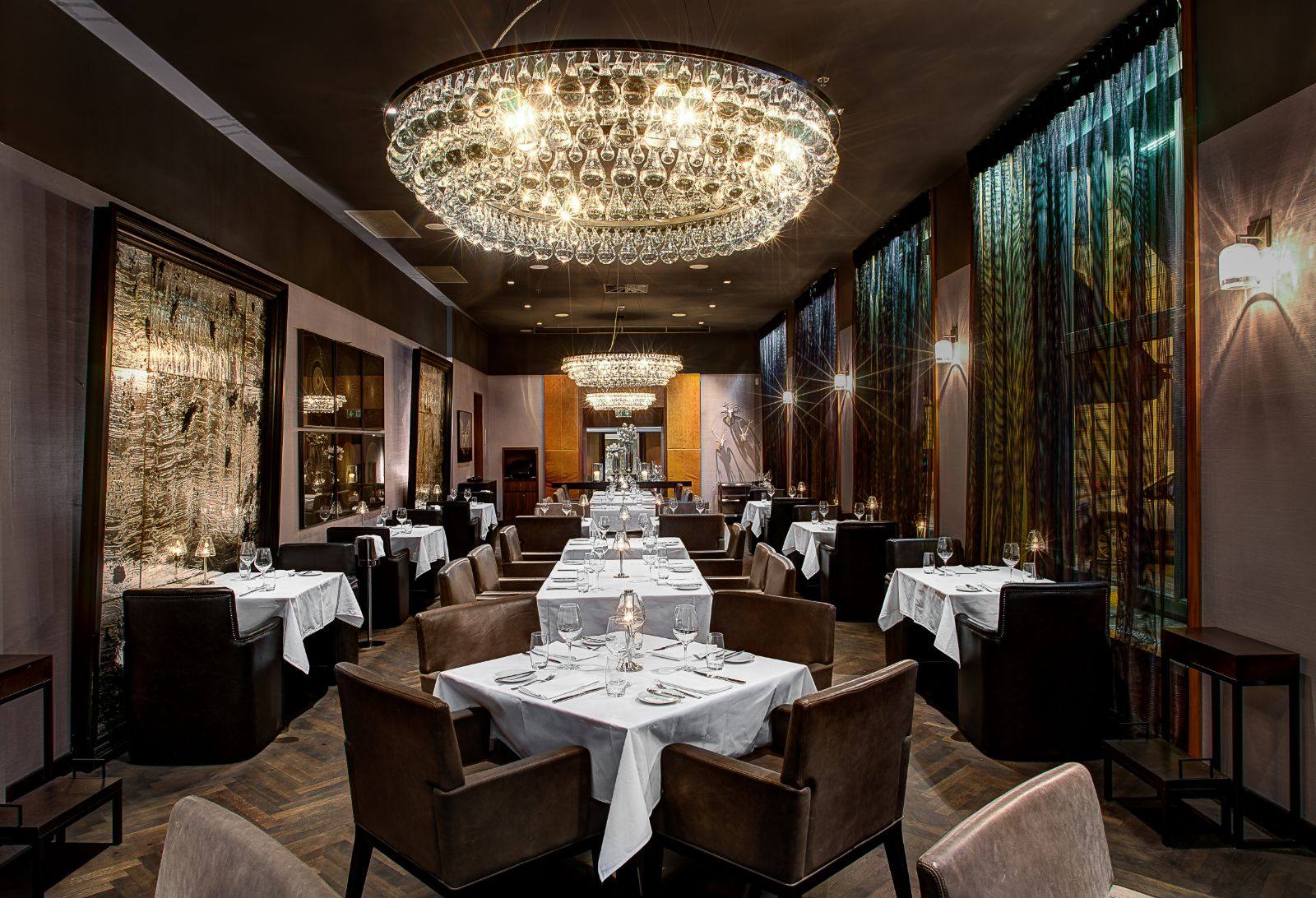 The dining room at George Prime Steak, with a crystal chandelier over white-clothed tables