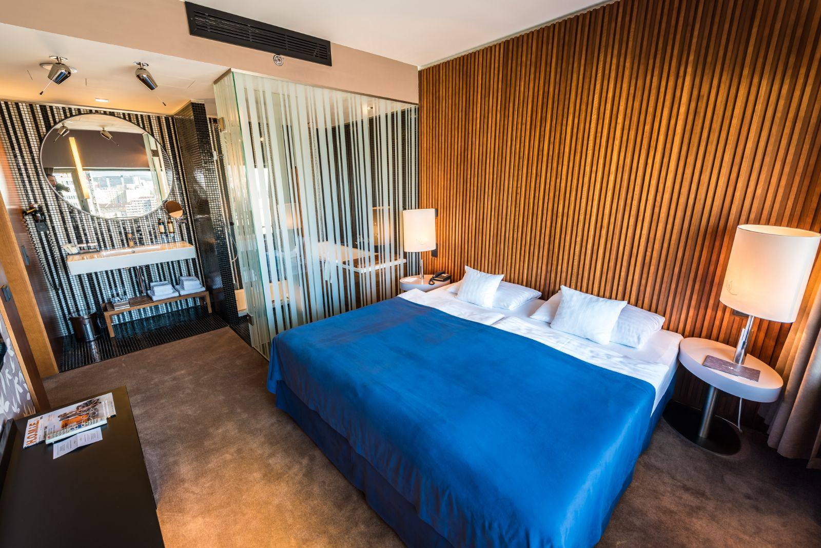 A guest room at Hotel Yasmin, with a slatted wood wall and glass-screened bathroom