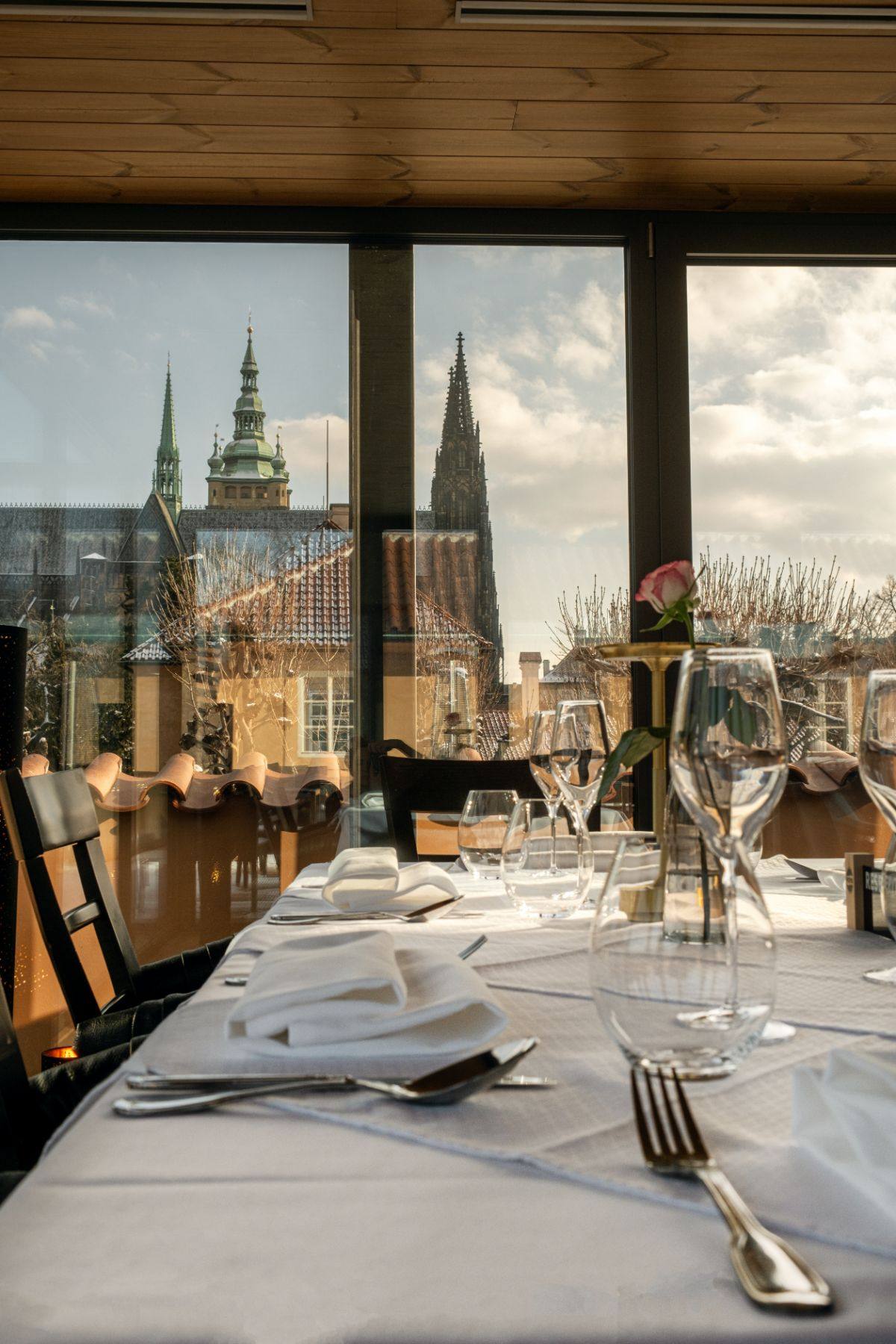 A set table at Lví Dvůr with St. Vitus Cathedral beyond the windows