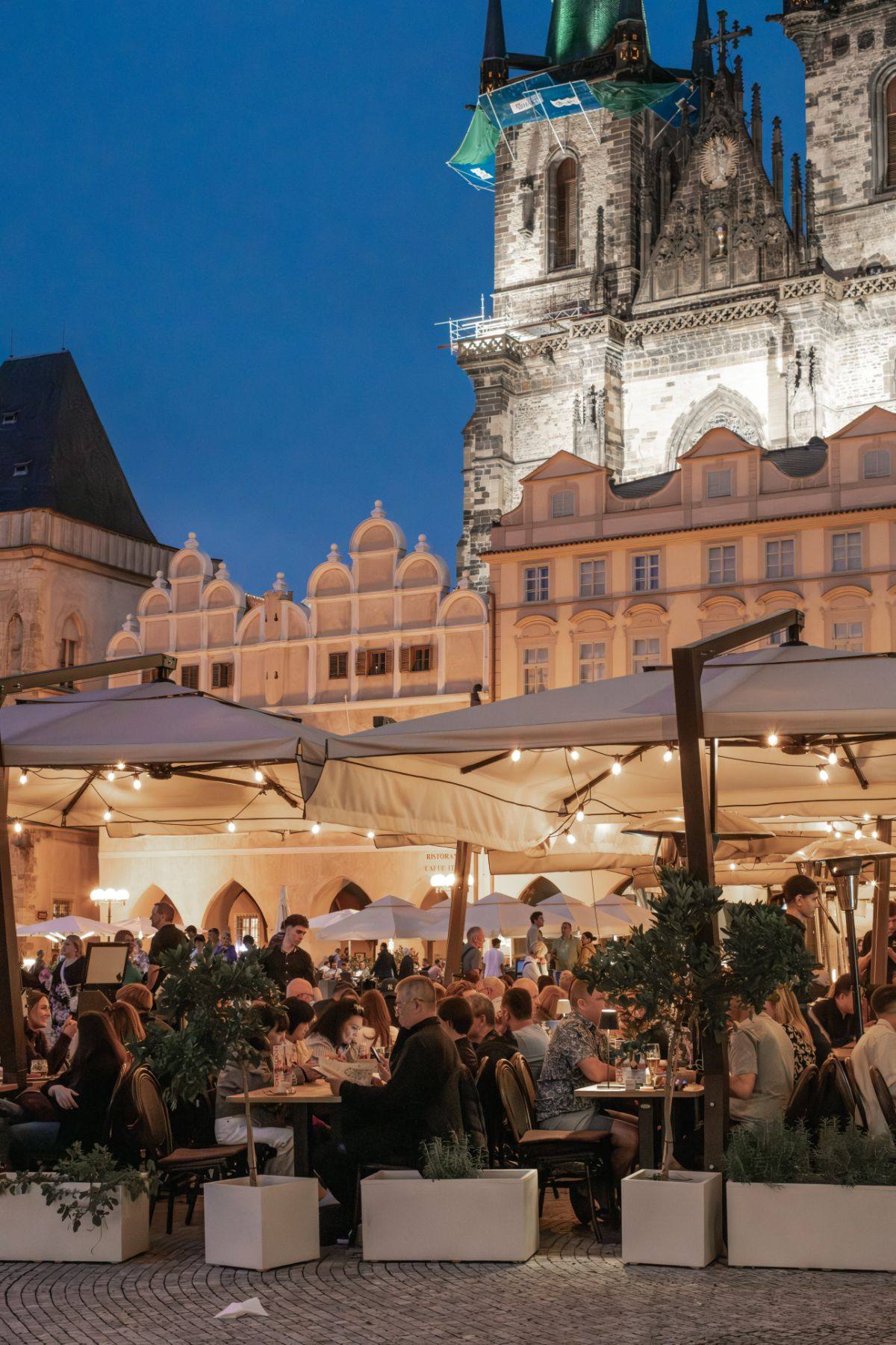 White Horse terrace on Old Town Square in the evening, with Týn Church behind